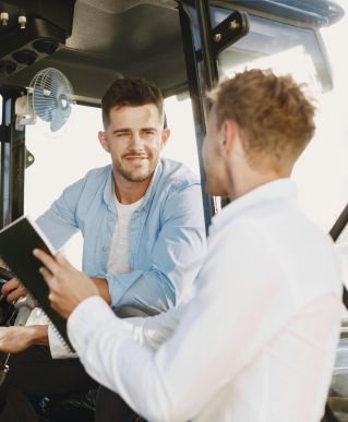 Two men collaboratively discussing inside machinery cabin, fostering teamwork.